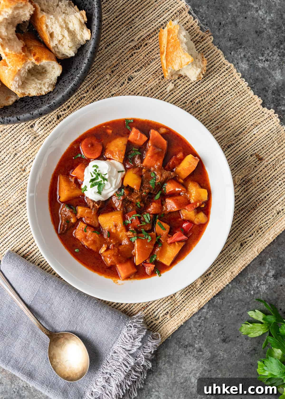 Traditional Hungarian Goulash Recipe: Hearty Beef Stew Guide 13 overhead: my hungarian goulash recipe in a white bowl with sour cream on top and baguette on the side