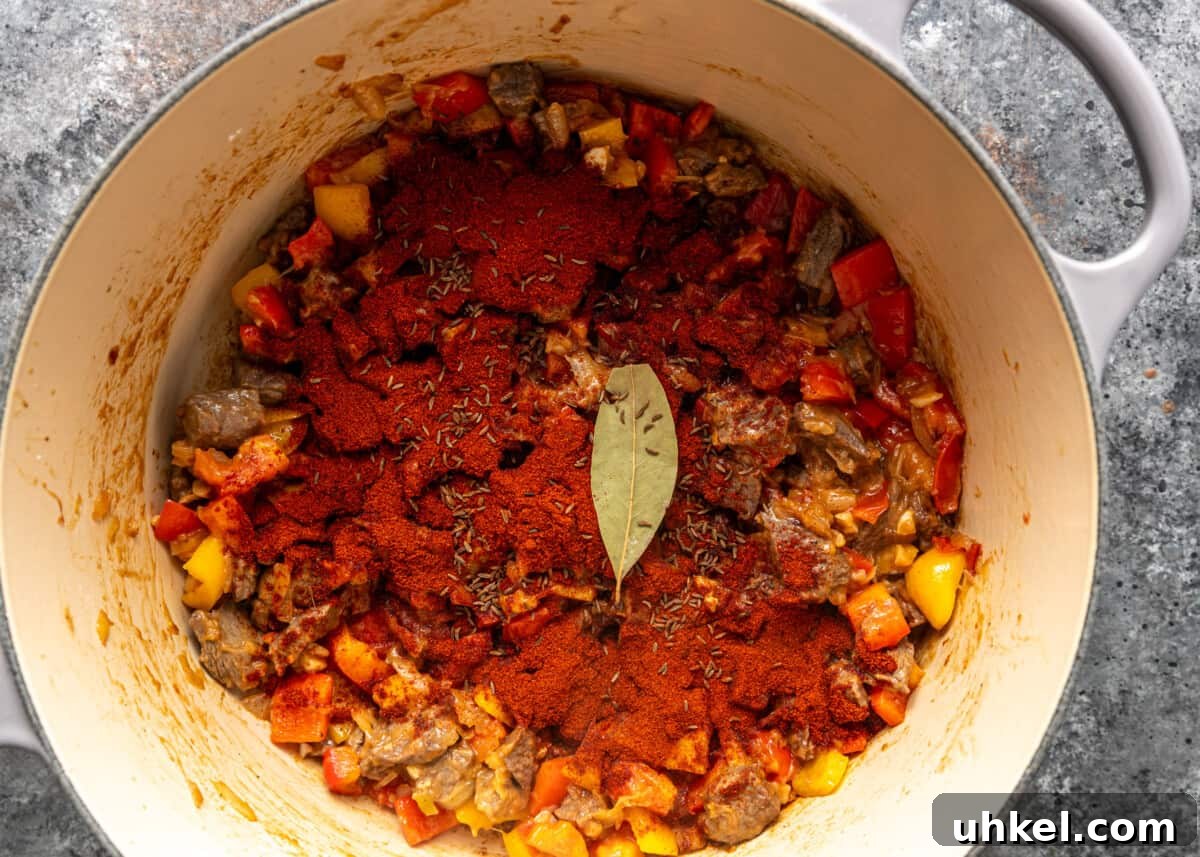 Traditional Hungarian Goulash Recipe: Hearty Beef Stew Guide 8 overhead process shot: seasonings added to vegetables and beef