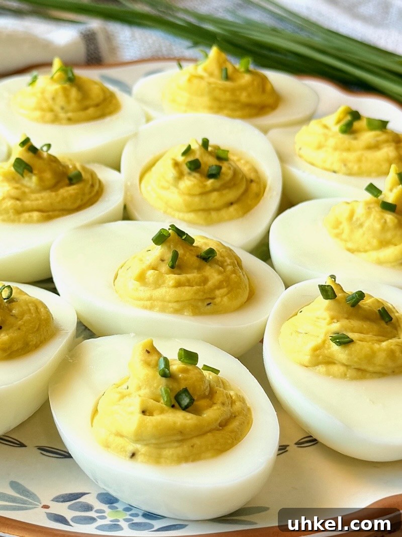 Classic Deviled Eggs Recipe for Gatherings 2 Deviled eggs prepared on a plate with chives on top.