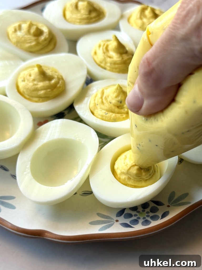 Classic Deviled Eggs Recipe for Gatherings 14 Pipping yolk filling into each egg while halve.