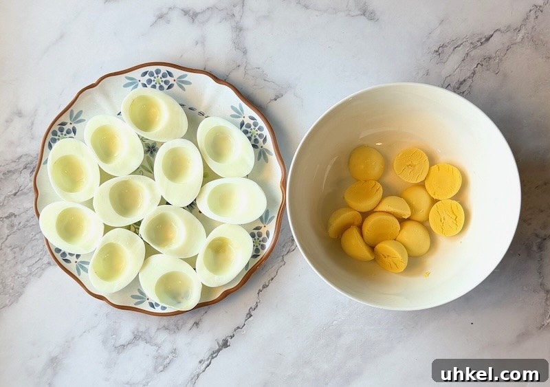 Classic Deviled Eggs Recipe for Gatherings 9 Halved hard egg whites on a plate and cooked egg yolks in a bowl
