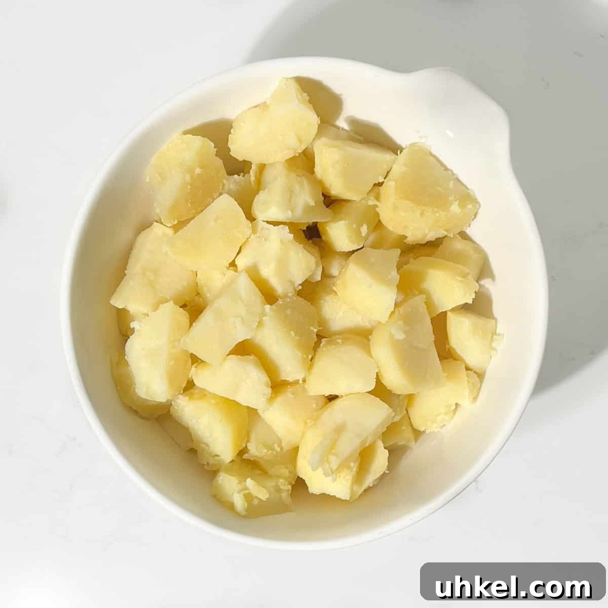Creamy Potato Salad with Sweetened Condensed Milk Recipe 5 Cooked potato cubes in a large white bowl.