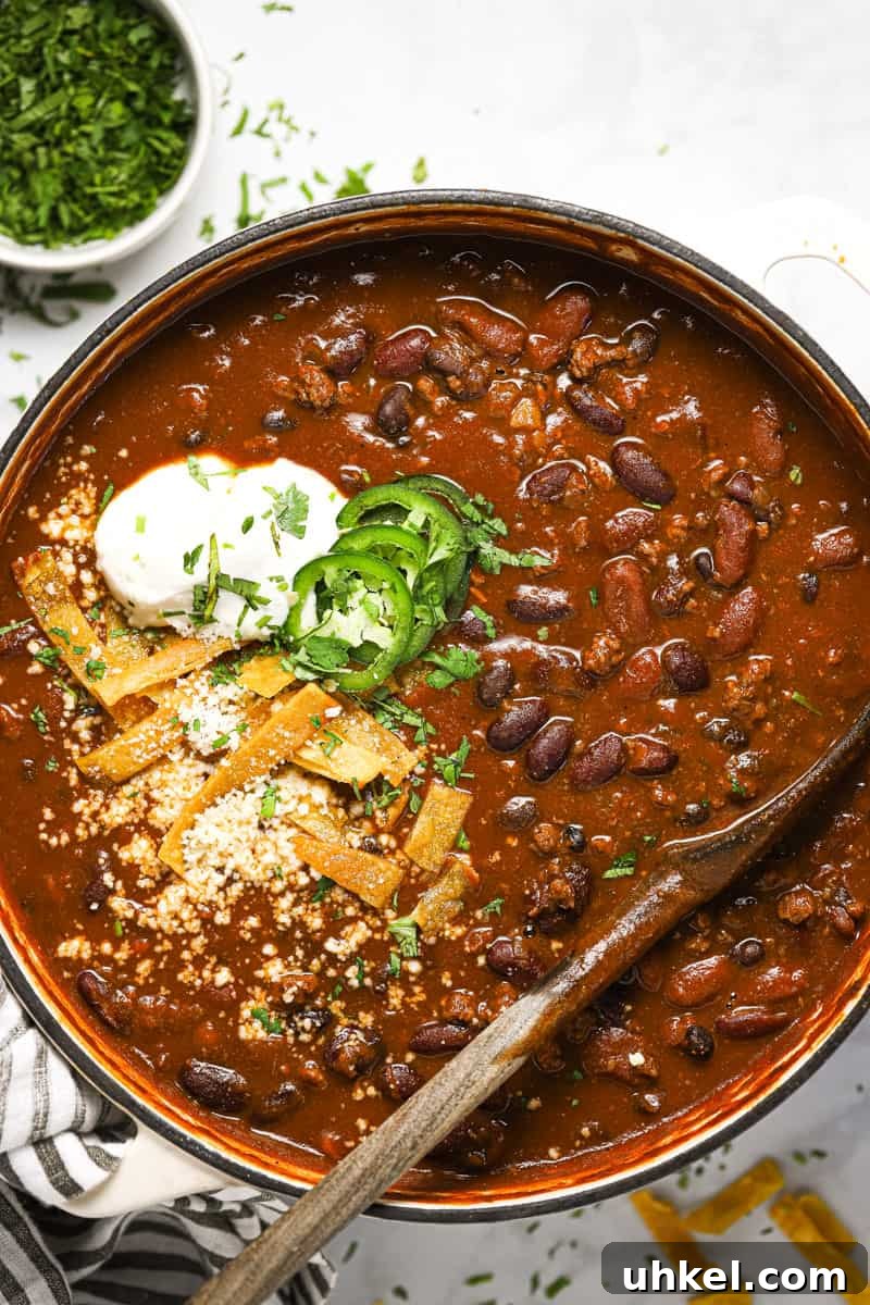 Large white pot filled with beer chili garnished with cilantro and tortilla strips
