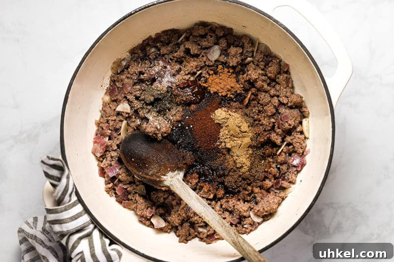 Large white pot filled with cooked ground beef and spices