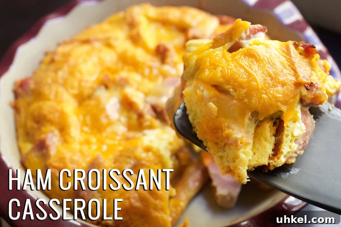 Ham and Cheese Croissant Casserole: Quick Savory Breakfast Bake 2 A spatula holds up a piece of ham and croissant breakfast casserole with the casserole dish in the background