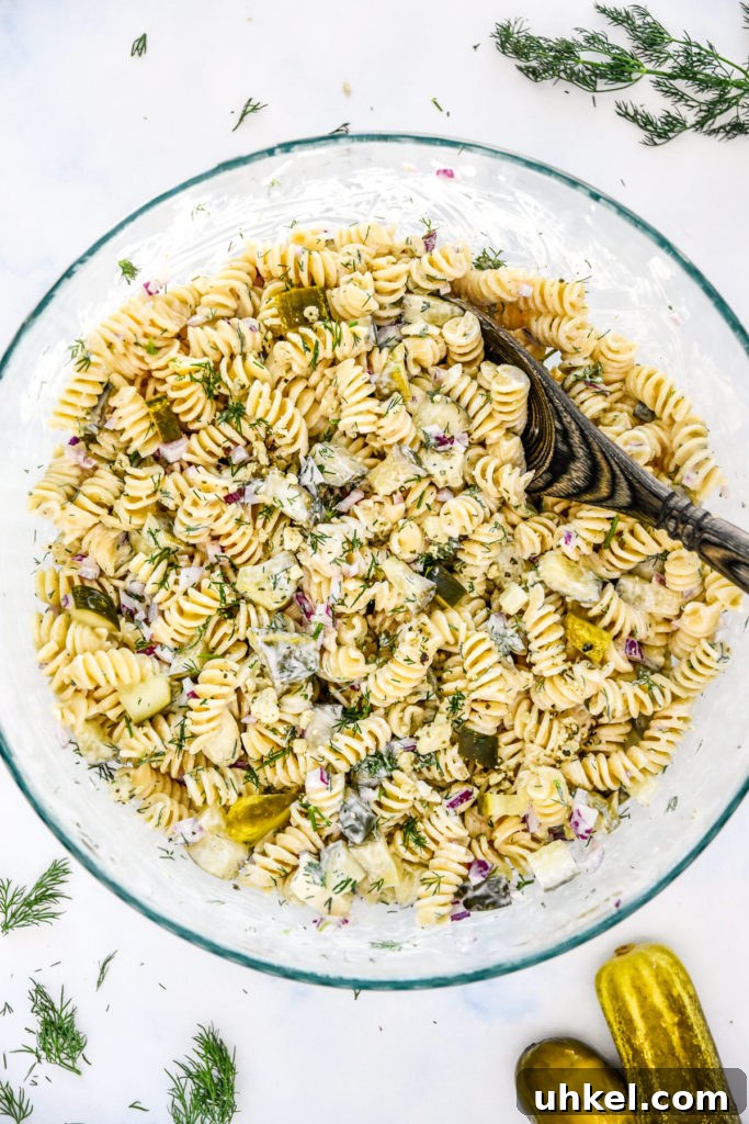 Creamy Dill Pickle Pasta Salad Recipe for Summer Potlucks 7 creamy dill pickle pasta salad in a large glass serving bowl with wooden spoon.