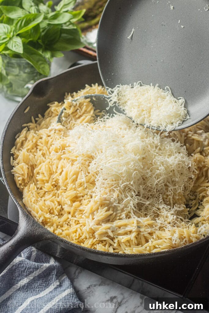 Creamy Orzo with Oven-Roasted Asparagus and Parmesan 5 Pouring grated parmesan cheese onto cooked orzo.