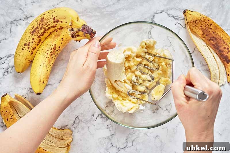 Out of Oil? How to Bake Without It Using Smart Substitutes 6 Horizontal image of mashing bananas in a glass bowl.