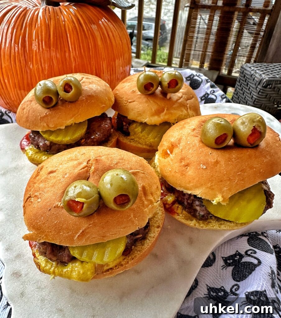 Spooky Onion Butter Burgers for Halloween Party Night 2 Four burgers with olive 'eyes' in front of a pumpkin.