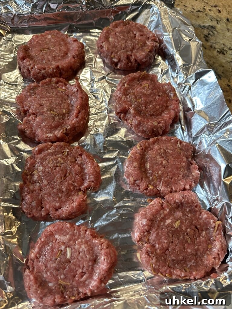 Spooky Onion Butter Burgers for Halloween Party Night 4 Raw beef patties on a foil lined baking sheet.
