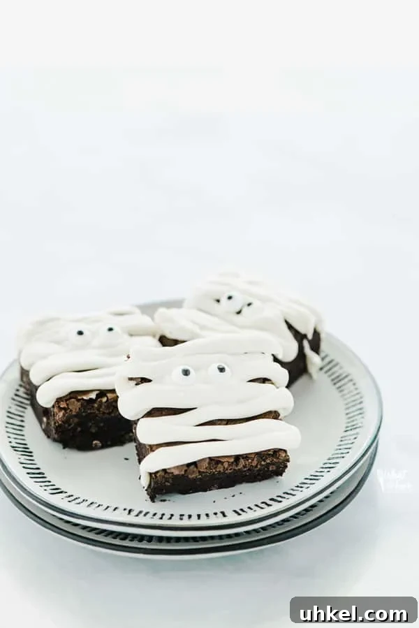 three gluten free mummy brownies on a stack of 2 plates
