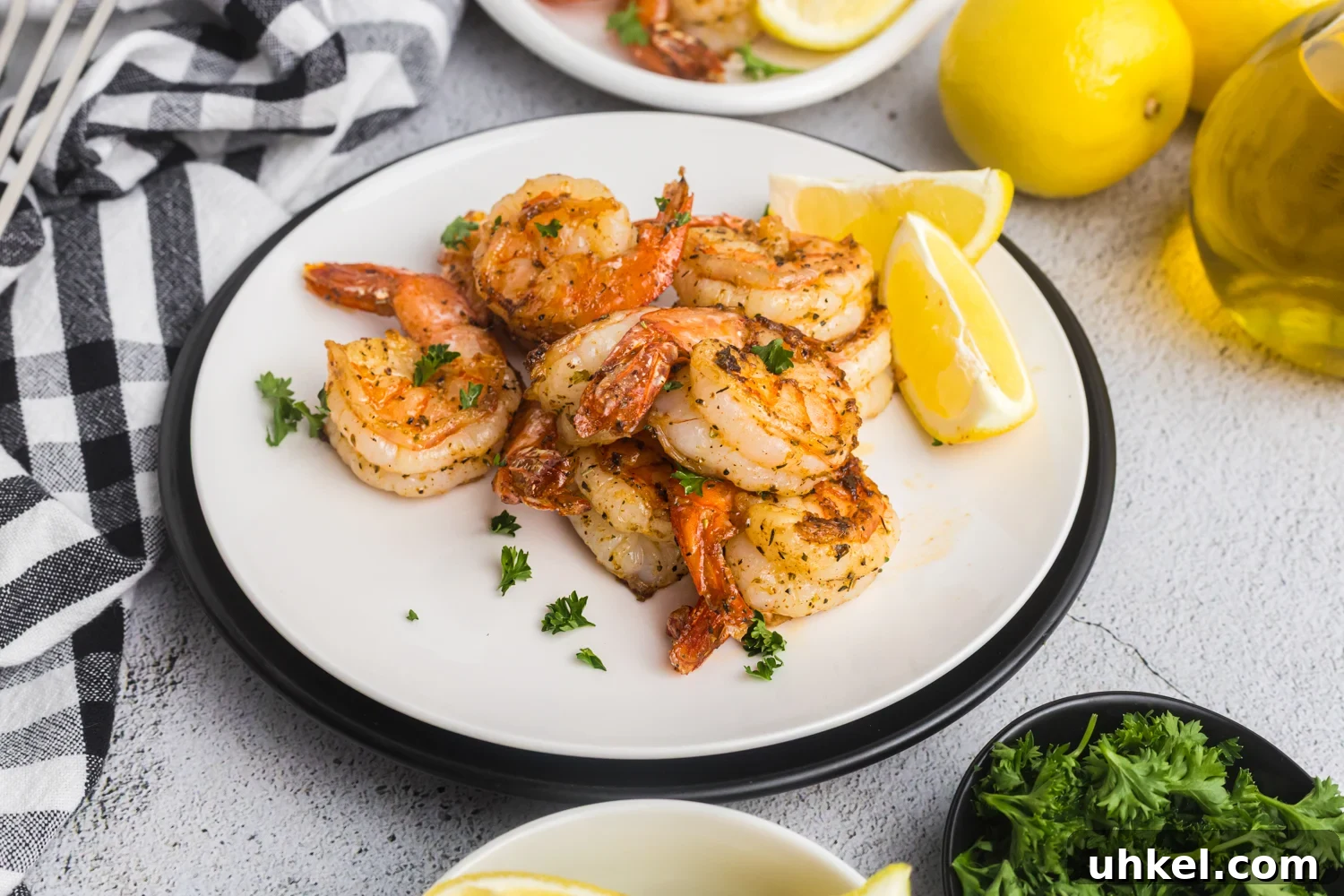 Cooked shrimp served on a white plate with lemon wedges and parsley, ready to eat.