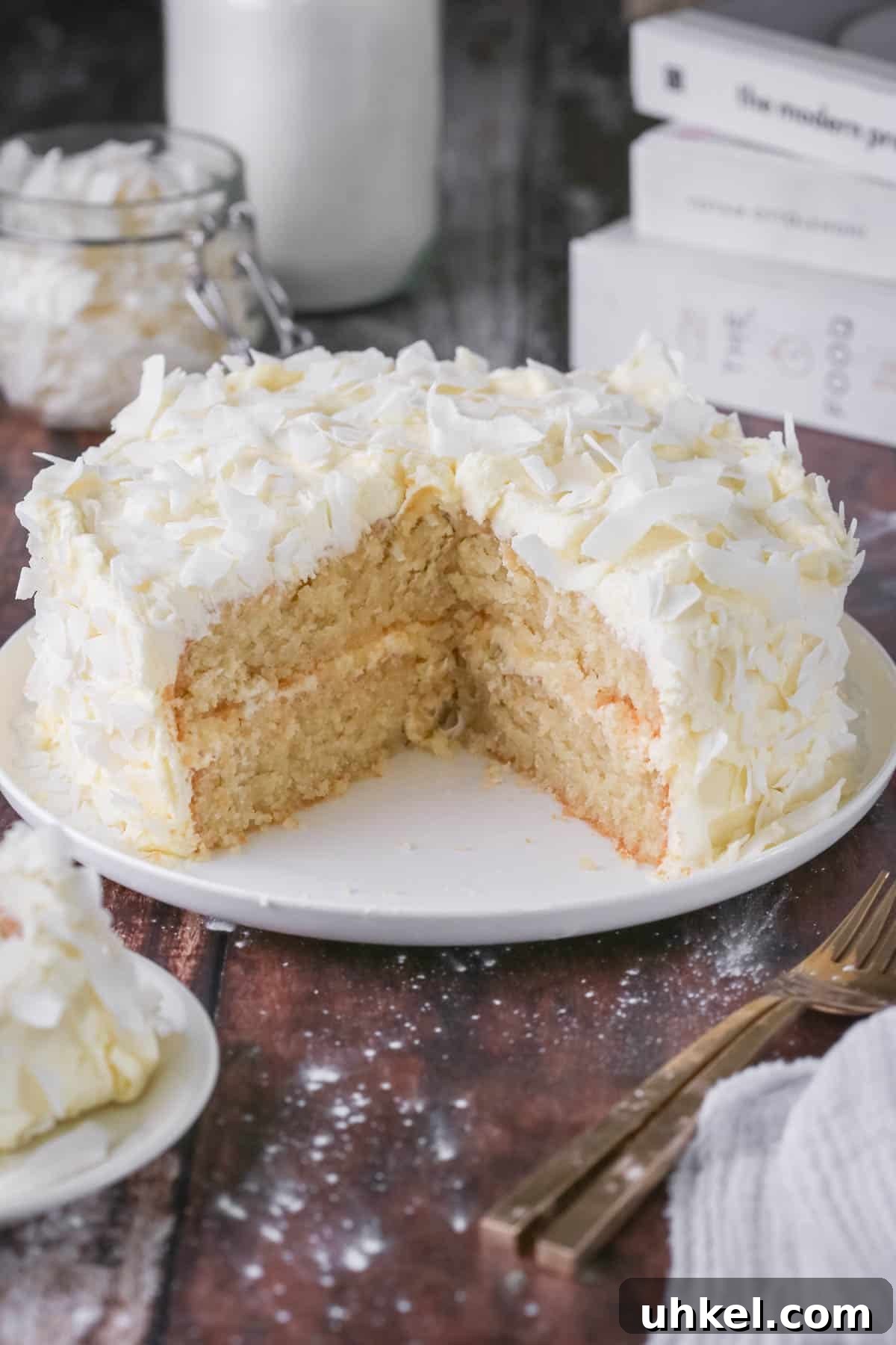Coconut Cake Without Gluten: Moist Recipe for Allergy-Friendly Celebrations 2 Gluten-Free Coconut Cake covered in coconut flakes on a white plate. Cut into showing soft moisture texture.