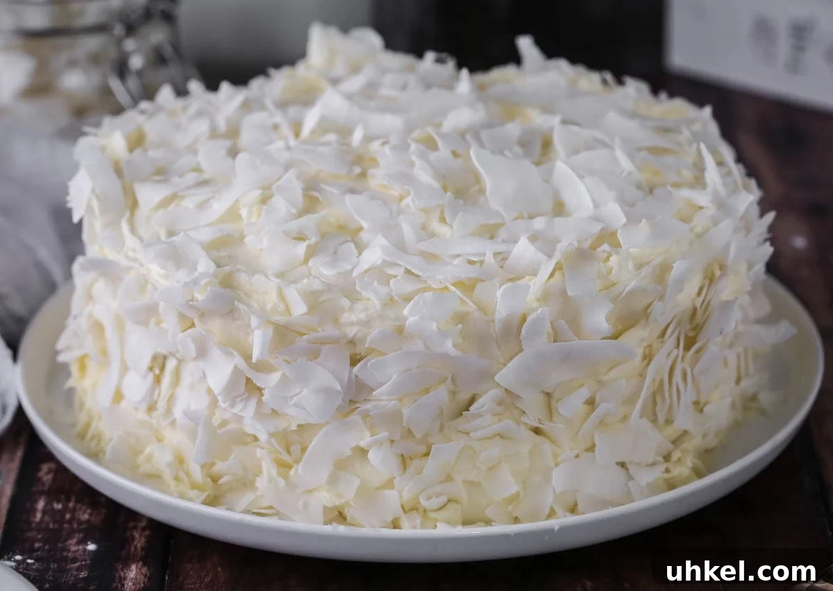 Coconut Cake Without Gluten: Moist Recipe for Allergy-Friendly Celebrations 5 Gluten-Free Coconut Cake covered in coconut flakes on a white plate.