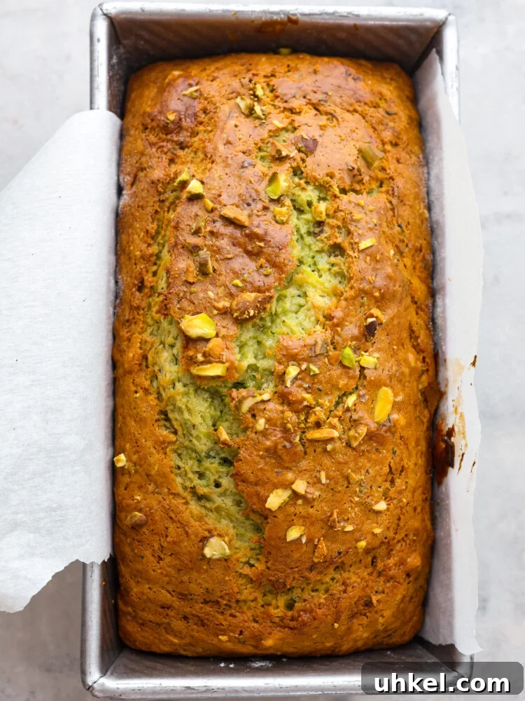 This deliciously soft pistachio zucchini bread is the perfect twist on a classic recipe. Packed with tons of unique flavor combinations from the pistachios and zucchini, you will LOVE this bread! The top view of pistachio zucchini bread in a loaf pan, baked and ready to eat.