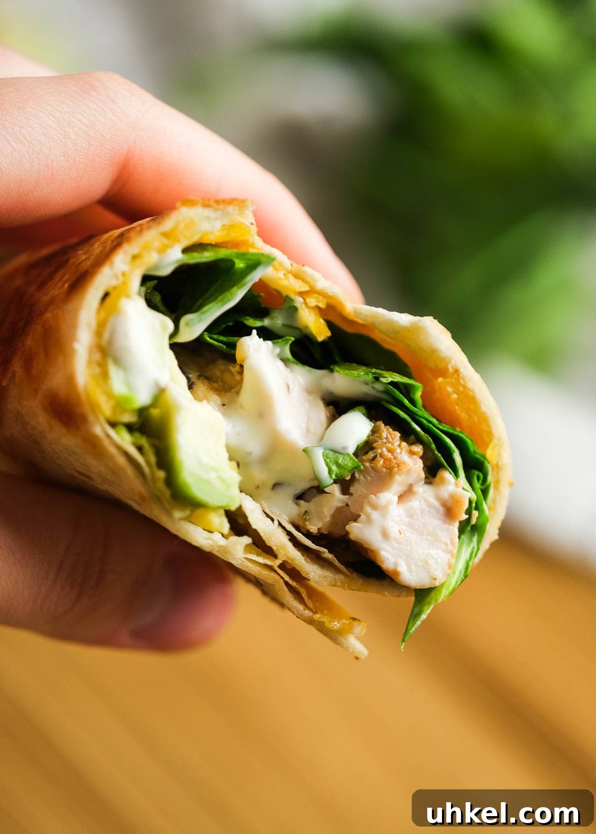 Chicken and Avocado Wrap Recipe for Quick Weeknight Meals 8 chicken avocado wrap being held in hand with wooden cutting board in background