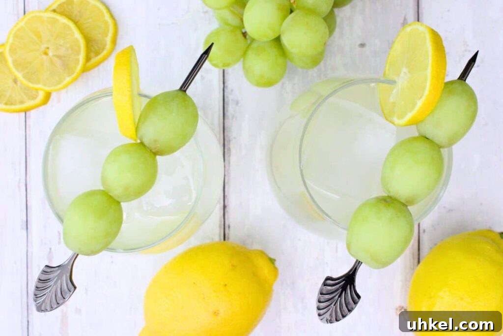 Cîroc Lemonade Spritzer Recipe — Refreshing Vodka Limonata Spritz 7 overhead view of two vodka lemonade spritzer cocktails garnished with lemon and grape skewer