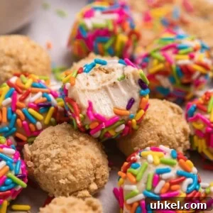 Bite shot of sprinkle covered no bake cheesecake ball arranged with other cheesecake balls.
