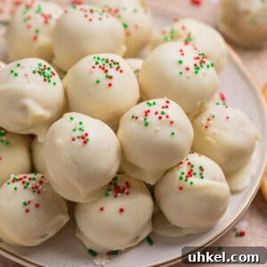 Plate with white chocolate covered Christmas Oreo cookie truffles topped with red, white and green sprinkles.