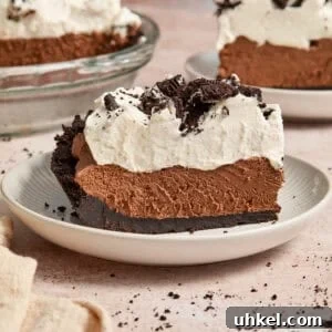 Slice of chocolate pie with chocolate Oreo crust and whipped cream topping.
