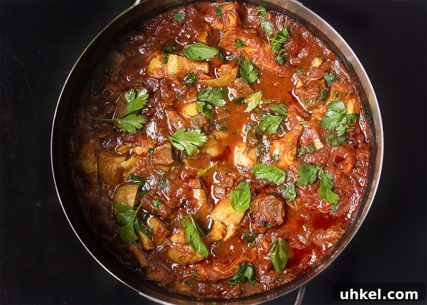 Lamb and Artichoke Stew Top view of a big pot of spring Greek lamb stew with artichokes and fresh herbs.