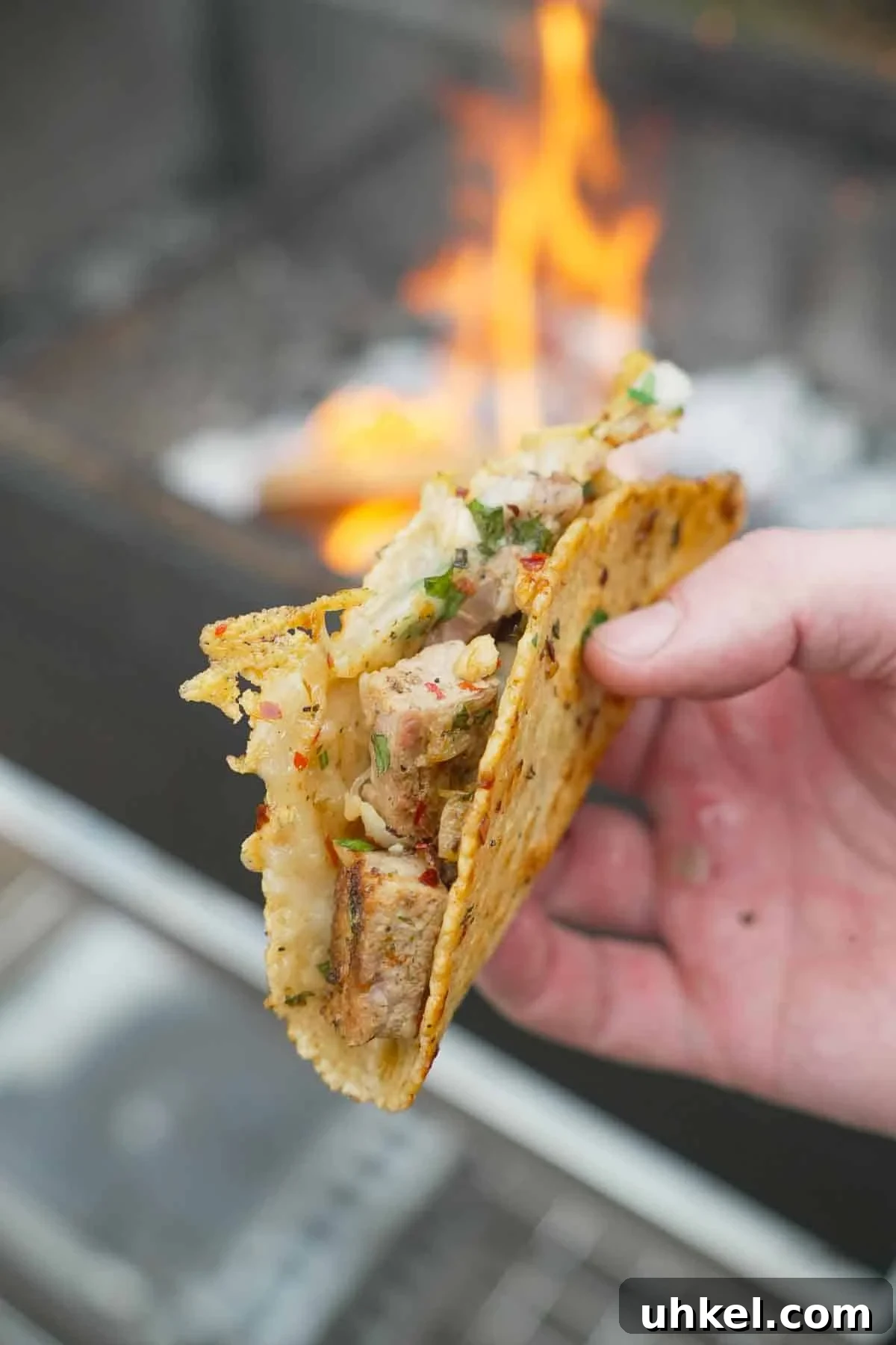 Garlic Shrimp Tacos with Spanish Flavors 3 A close up of a hand holding a single Spanish garlic taco with pork, cheese and garlic oil