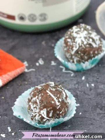 Featured image of three chocolate protein balls in blue cupcake liners with more on an orange linen behind them and a tub of protein powder