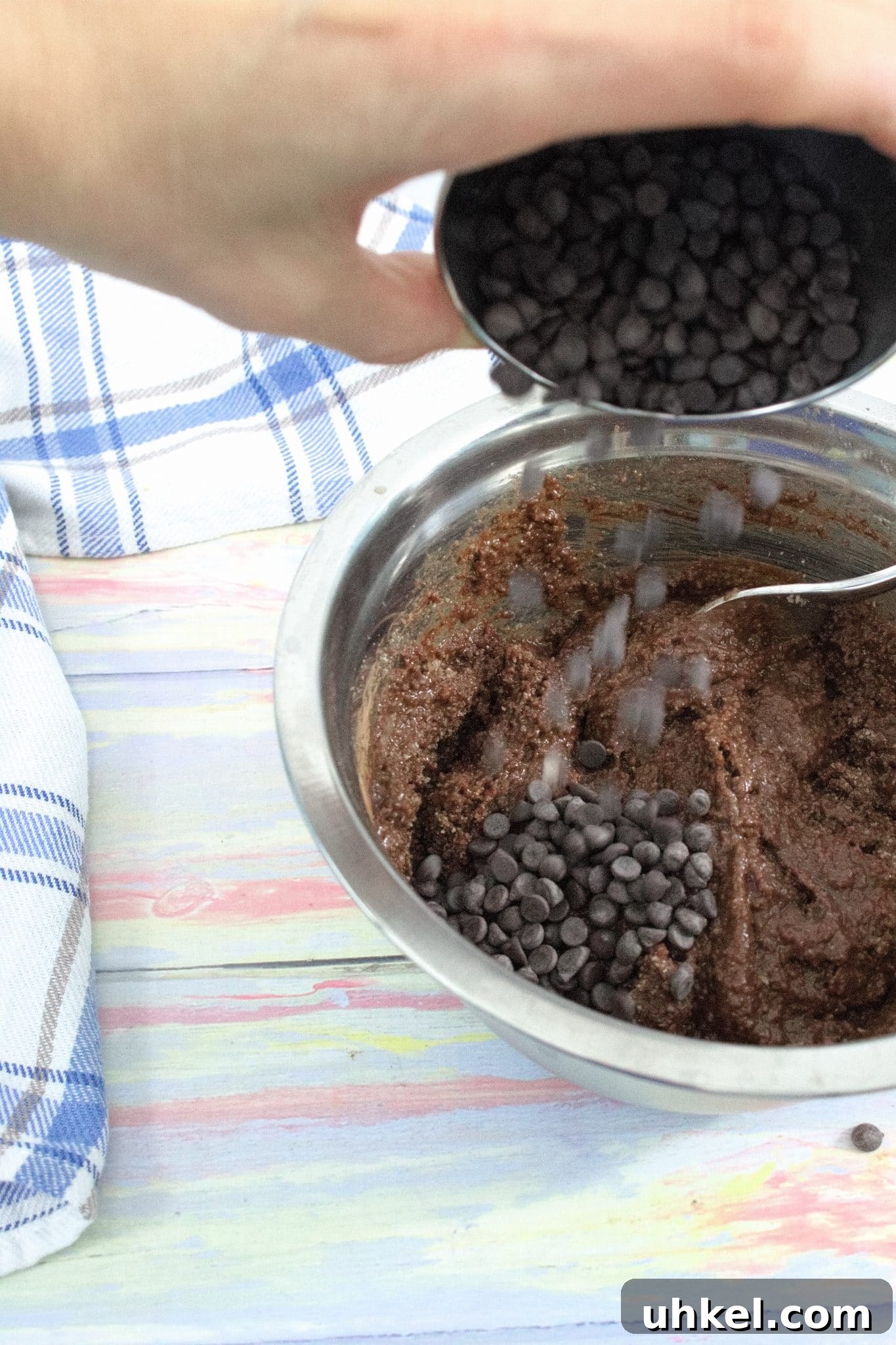 High-Protein Gluten-Free Brownies for Chocolate Lovers 6 Steel bowl of raw brownie batter with mini chocolate chips being poured in