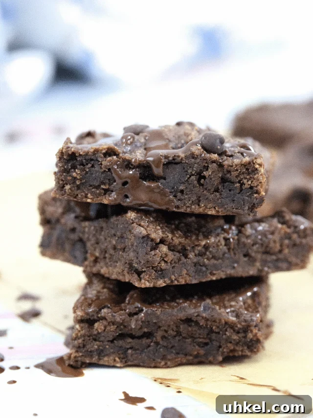 High-Protein Gluten-Free Brownies for Chocolate Lovers 8 Three gluten-free chocolate brownie squares stacked with a faint image of brownies and milk behind them