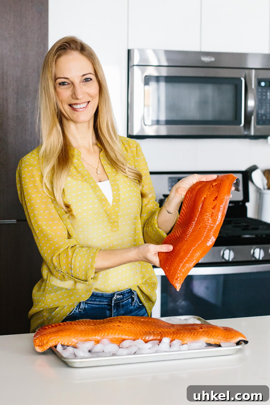 Wild-caught salmon versus farmed salmon - what's the difference? Let me tell you! Girl holding sockeye salmon filet in a kitchen.