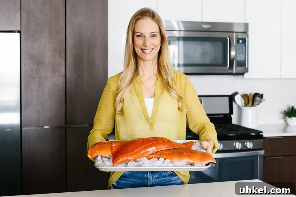 Wild-caught salmon versus farmed salmon - what's the difference? Let me tell you! Girl in kitchen holding sockeye salmon and king salmon on a platter.
