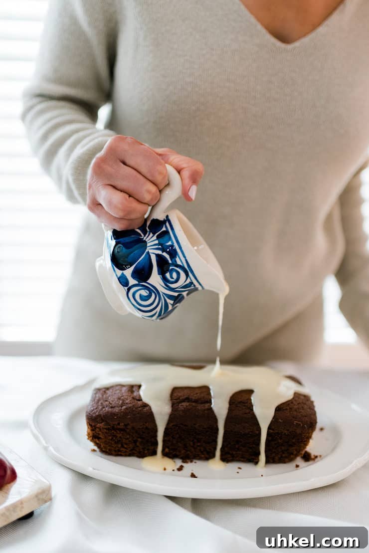 Moist Chocolate Loaf with Bourbon Glaze Recipe 5 bourbon glaze being pourers over a chocolate applesauce cake female wearing a beige winter sweater