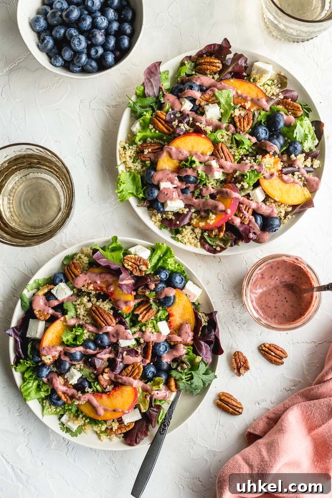 Summer peach salad with blueberries arranged on white plates and topped with blueberry peach balsamic dressing.