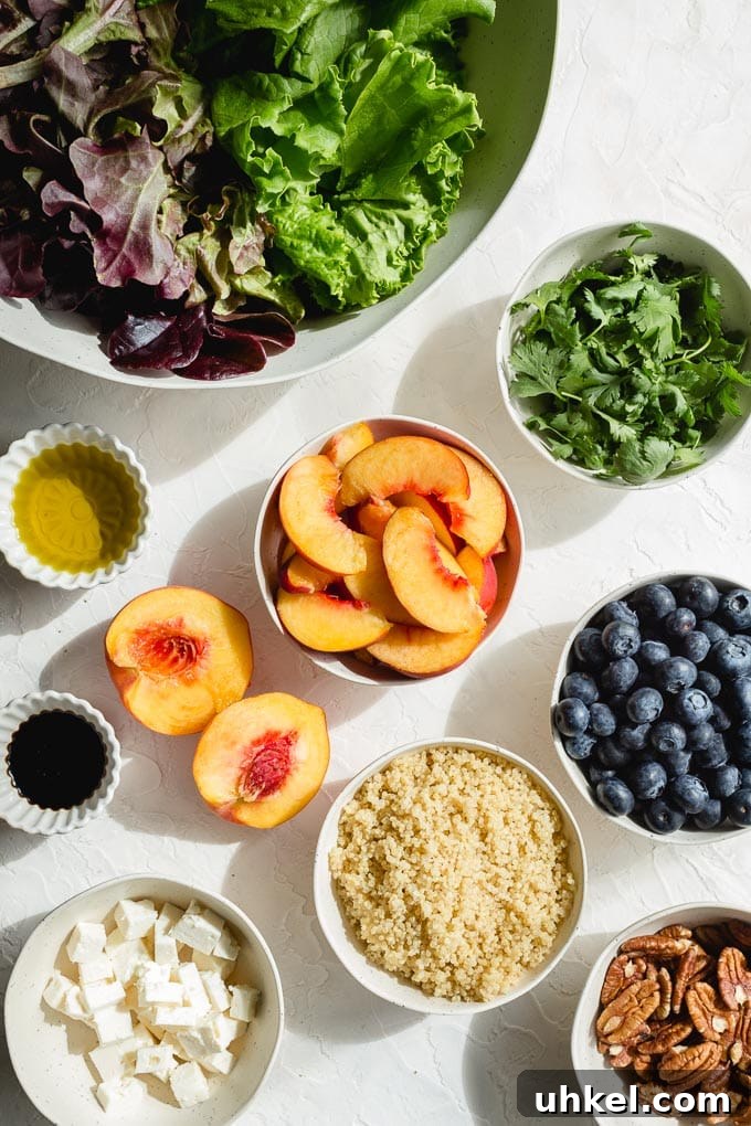 Ingredients to make blueberry peach salad arranged in individual bowls on a white surface.