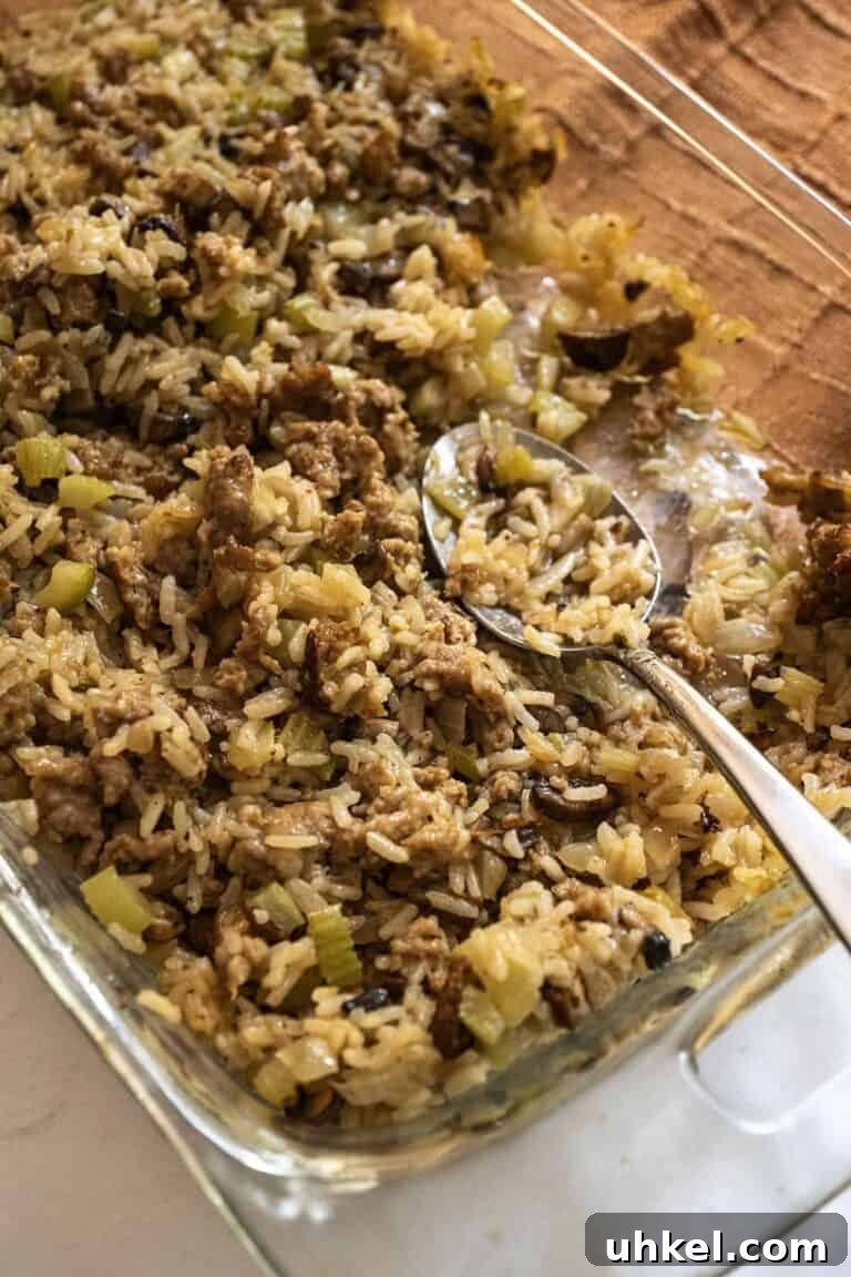 A serving spoon scooping up a serving of rice dressing from a baking dish. 