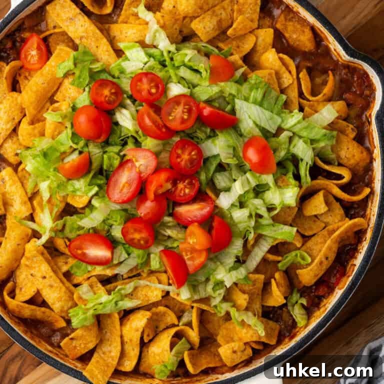 A pan of Frito taco casserole topped with shredded lettuce and tomatoes.