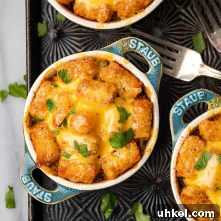Small crocks filled with Mexican tater tot casserole and topped with melted cheese.