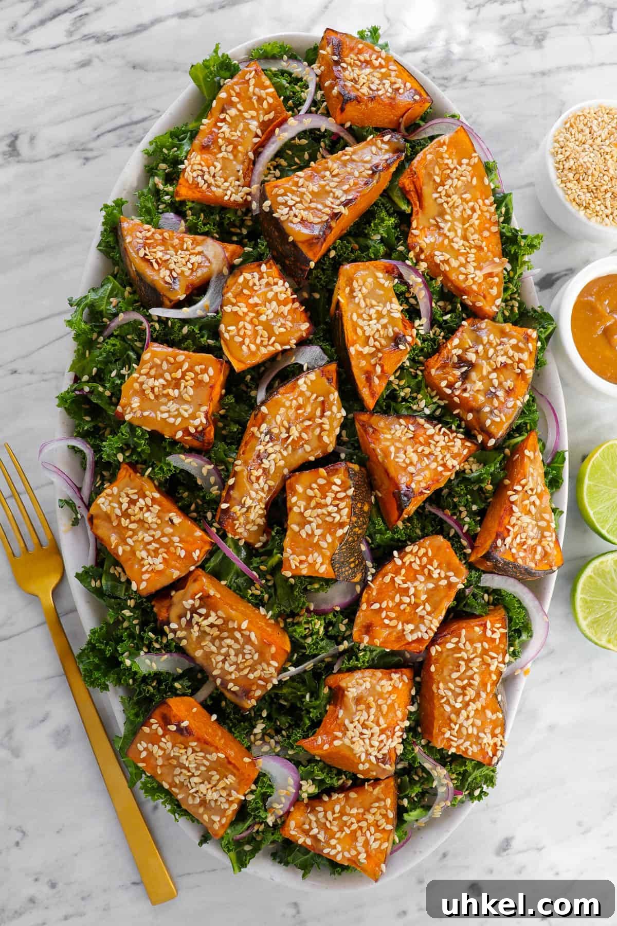 Miso-Glazed Pumpkin and Kale Salad with Toasted Seeds 4 Pumpkin salad with fork, limes, sesame seeds and tahini miso sauce on the side.
