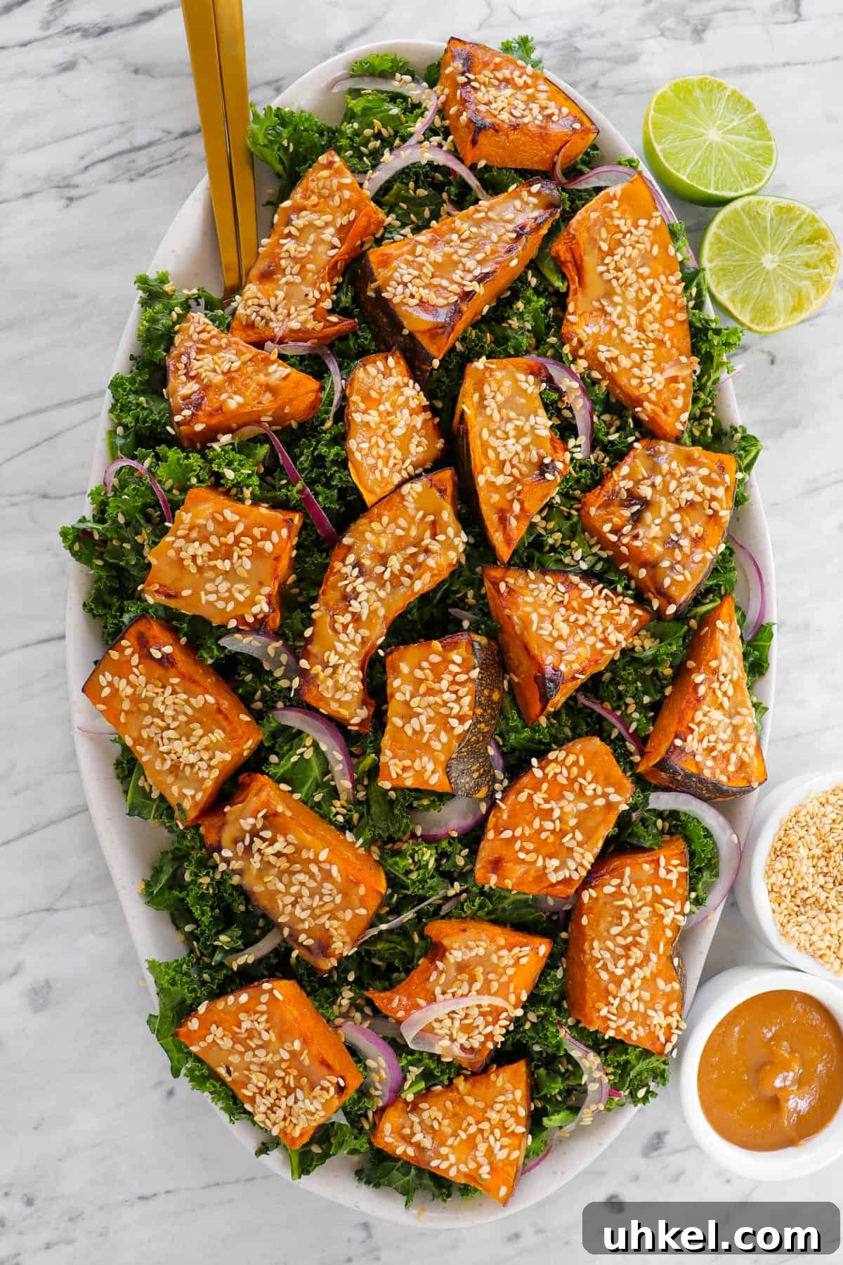 Miso-Glazed Pumpkin and Kale Salad with Toasted Seeds 8 Pumpkin salad with limes, sesame seeds and tahini miso sauce on the side. Cutlery in salad for decoration.