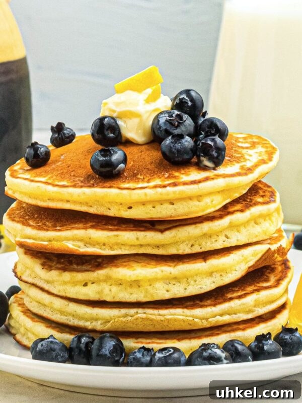 Classic Beanie Weenies Recipe with Flavorful Tomato Sauce 9 Golden fluffy pancakes stacked on a white plate, topped with blueberries and butter.