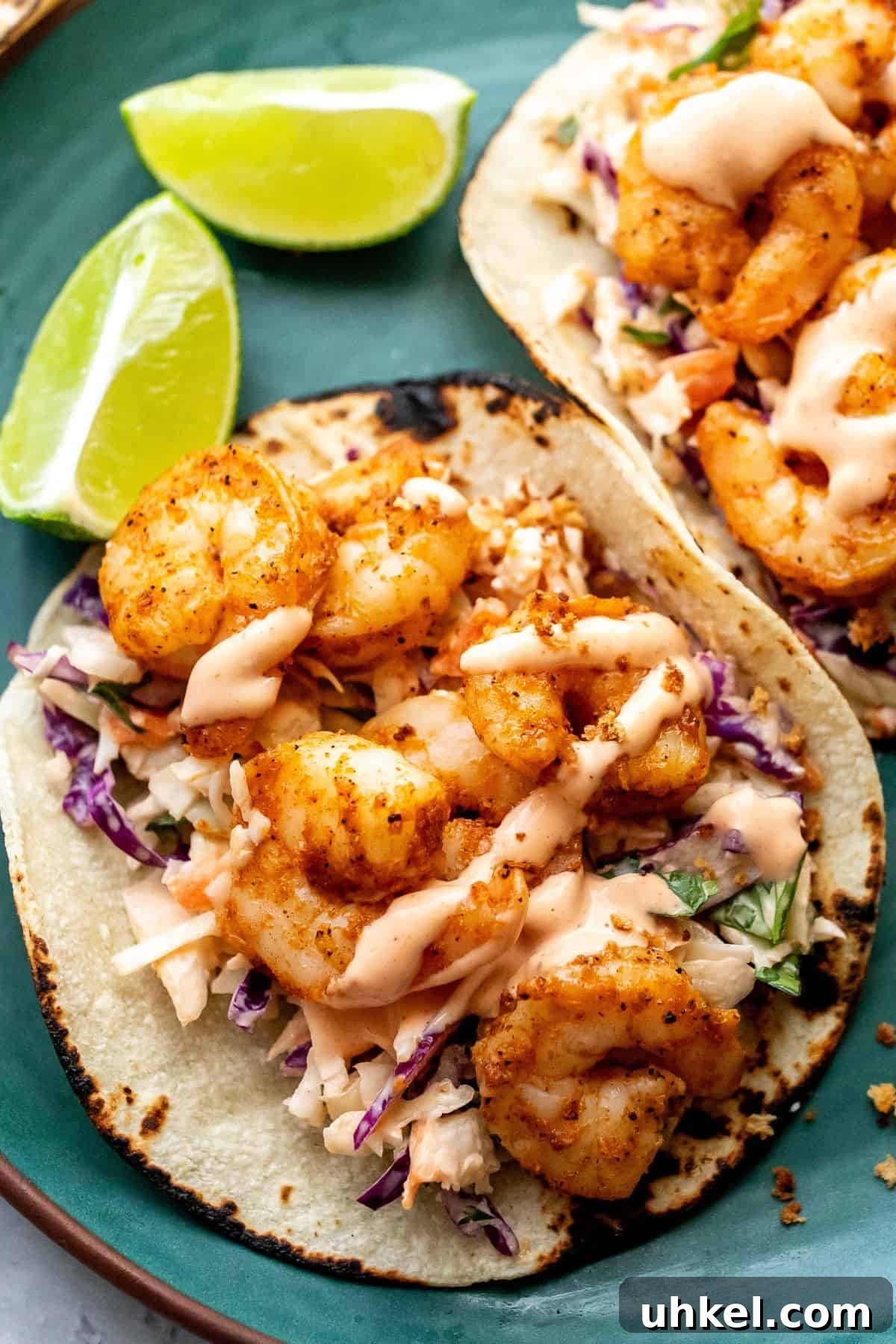 Crispy Baja Shrimp Tacos with Tangy Lime Slaw 5 Up close photo of the baja shrimp tacos with a lime on the side on a green plate.