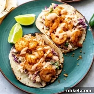 Crispy Baja Shrimp Tacos with Tangy Lime Slaw 10 Green plate with baja shrimp tacos on them and limes to the side.