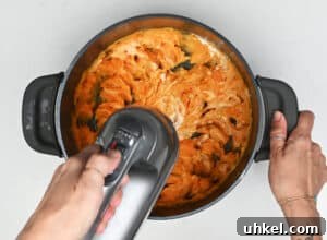whipping sweet potatoes in a pot with an electric hand mixer