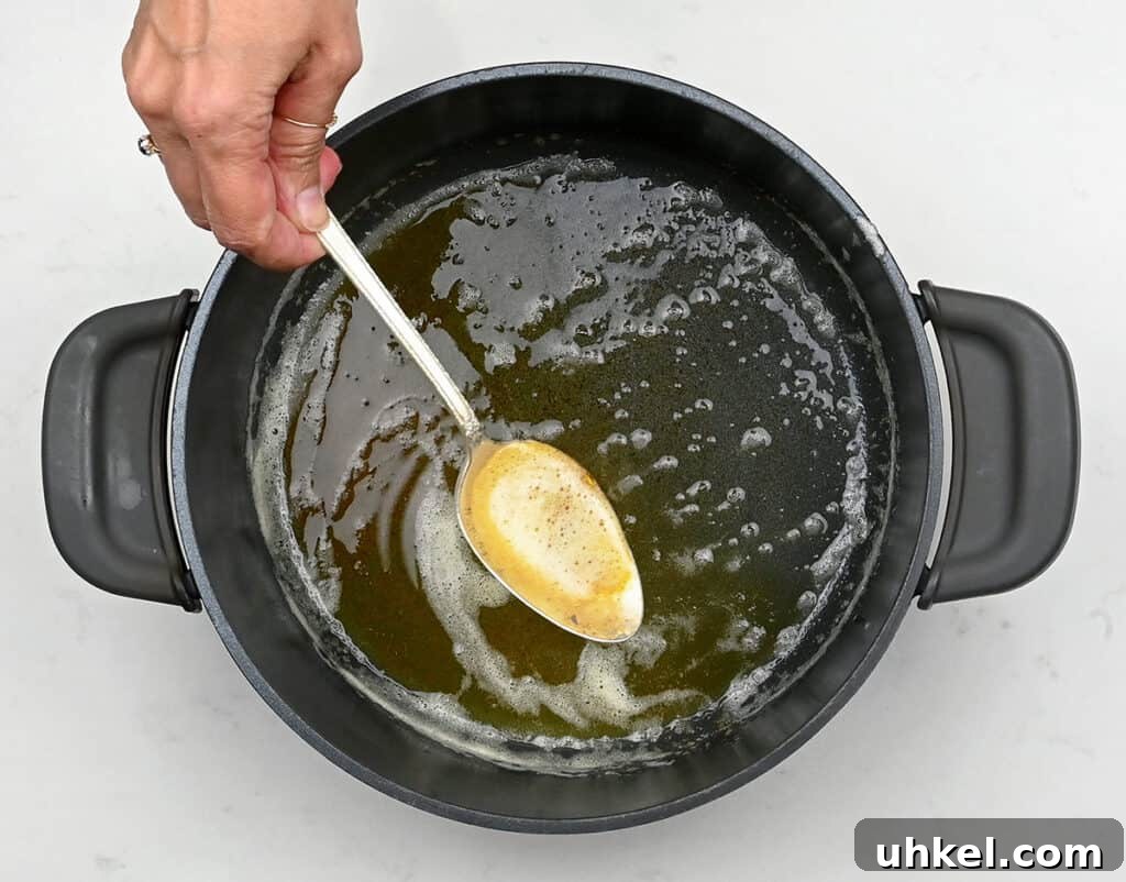 Spoon showing browned butter with pot underneat