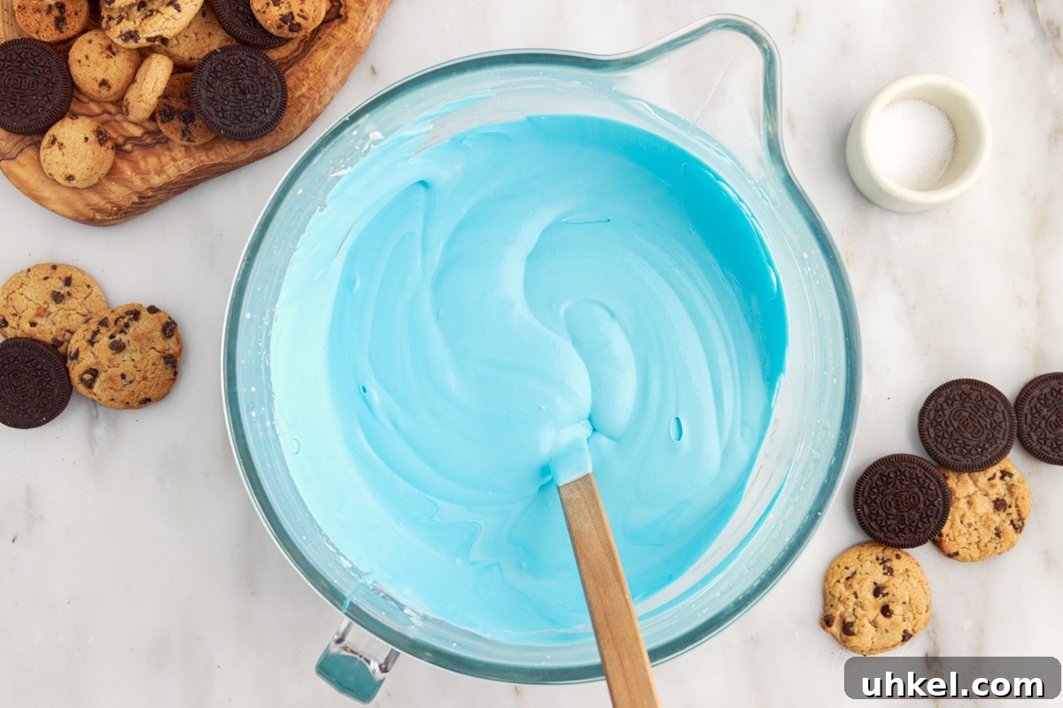 Heavy cream condensed milk mixture mixed together with a spatula inserted next to Oreo's and chocolate chip cookies.