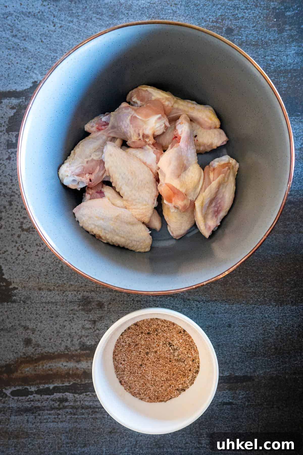 Savory Homemade Dry Rub Recipe for Crispy Chicken Wings 5 Chicken wings by bowl of dry rub seasoning.