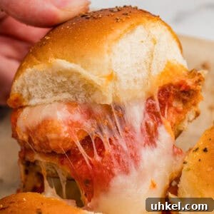 Chicken Parmesan Sliders Recipe: Crispy Mini Sandwiches 8 A chicken parm slider with nuggets and melty cheese being pulled from the pan.