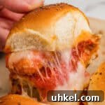 Chicken Parmesan Sliders Recipe: Crispy Mini Sandwiches 9 A chicken parm slider with nuggets and melty cheese being pulled from the pan.