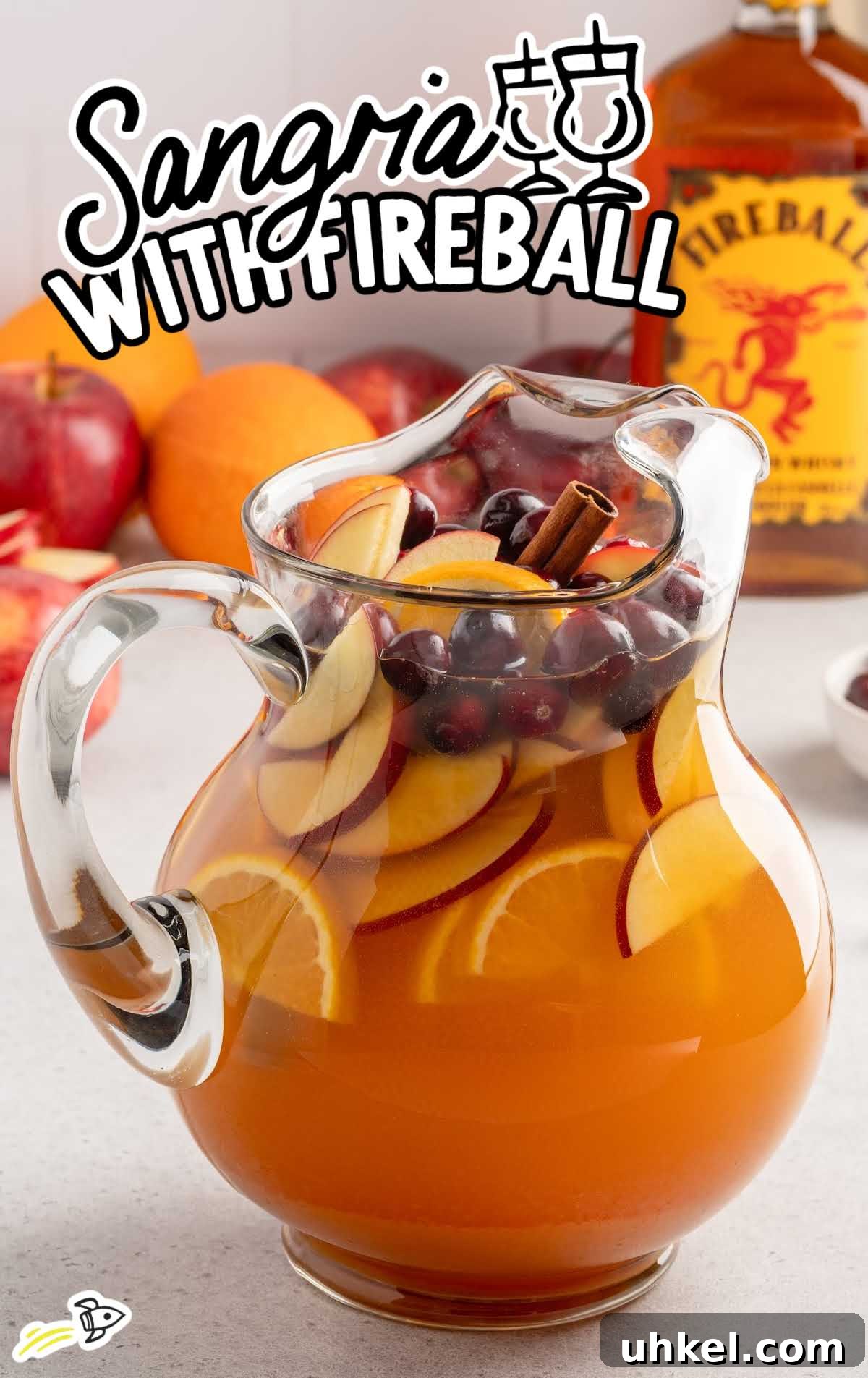 5-Minute Fireball Sangria Recipe for Quick Party Drinks 2 Large pitcher of apple cider sangria with Fireball whisky loaded with sliced apples, oranges, cranberries, and cinnamon sticks.