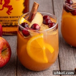 5-Minute Fireball Sangria Recipe for Quick Party Drinks 11 Close-up glass of Fireball apple cider sangria filled with oranges, apples, cranberries, and a cinnamon stick.